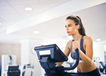 young female athlete training alone on treadmill in modern gym